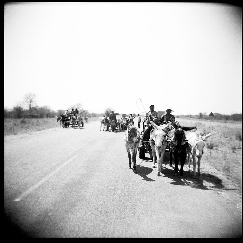 A black-and-white photograph © Annelize Bester, Mahalapye, Botswana, Africa, 2007, depicting three donkey-drawn water carts local residents collecting water.